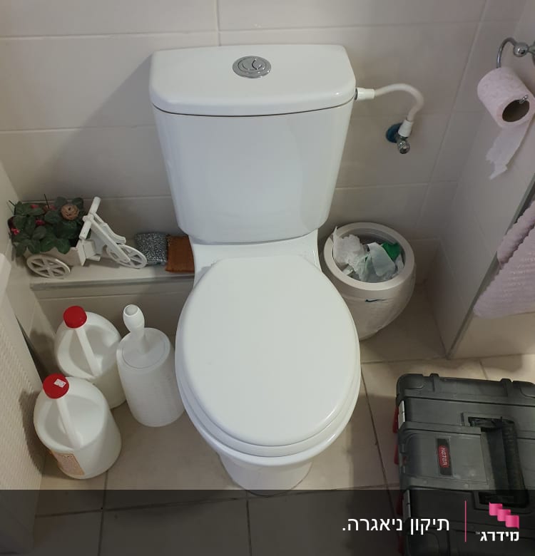 ארגז כלים ליד אסלה בחדר אמבטיה